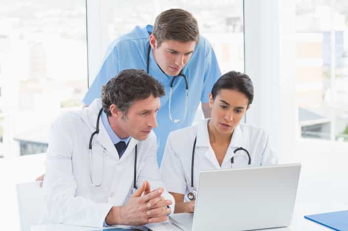 Team of doctors working on laptop computer in medical office-1